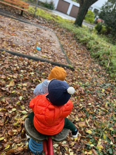 Kinder sitzen draußen auf einem Spielgerät