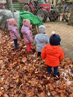 Kinder stehen im Herbstlaub an einem Zaun